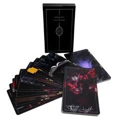 Deck of dark-themed tarot or oracle cards with artistic imagery spread out from its box.